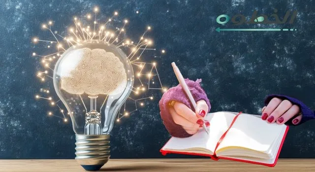 لمبة فكرة مضيئة مع يد بتكتب بمفكرة على خلفية داكنة ترمز لأفكار صناعة المحتوى.